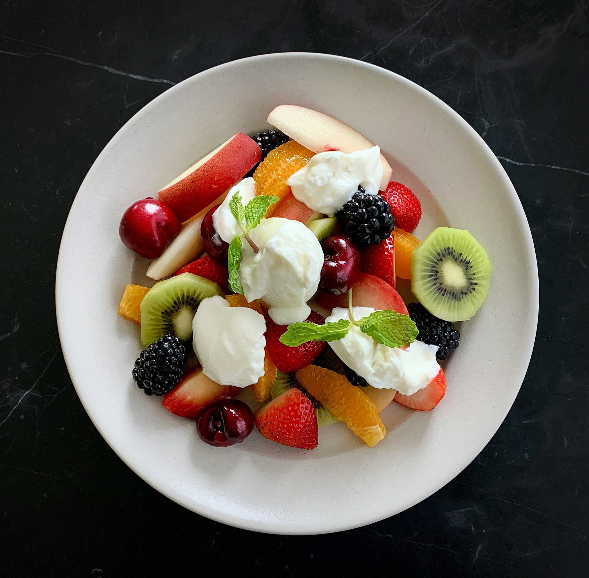 a white plate topped with fruit and whipped cream